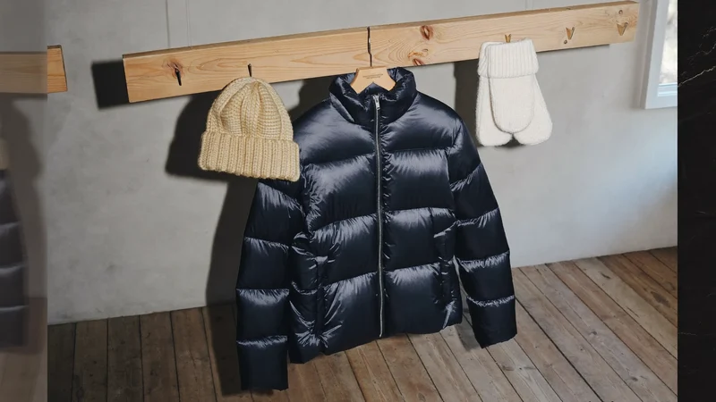 Piumino per bambini su gruccia accanto a cappello e guanti in maglia